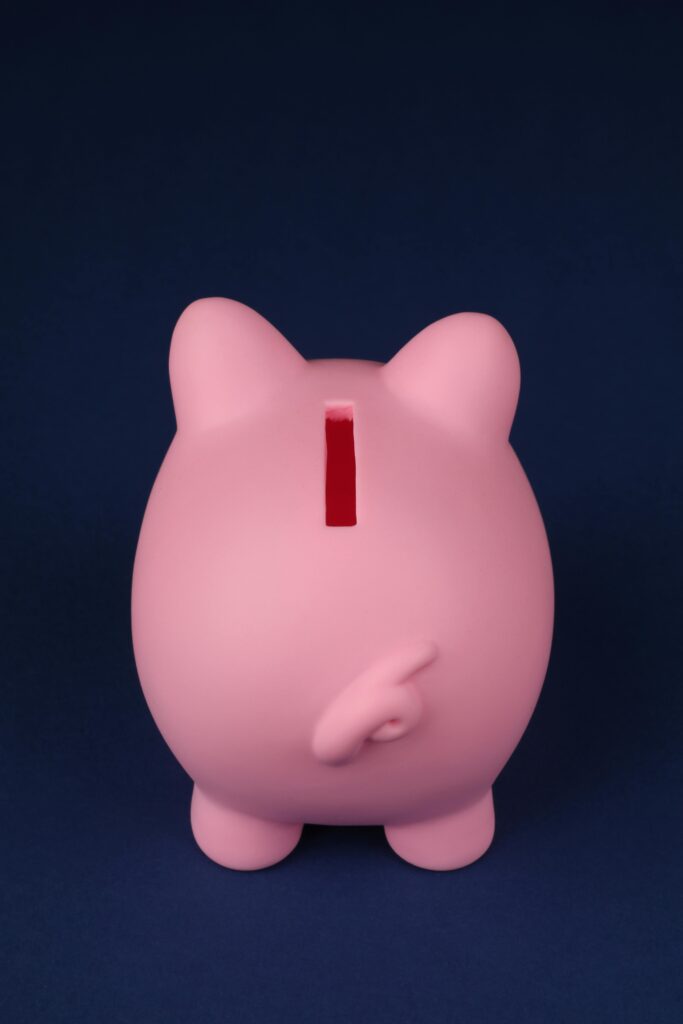 Back view of a pink piggy bank against a dark blue backdrop, highlighting savings concept.