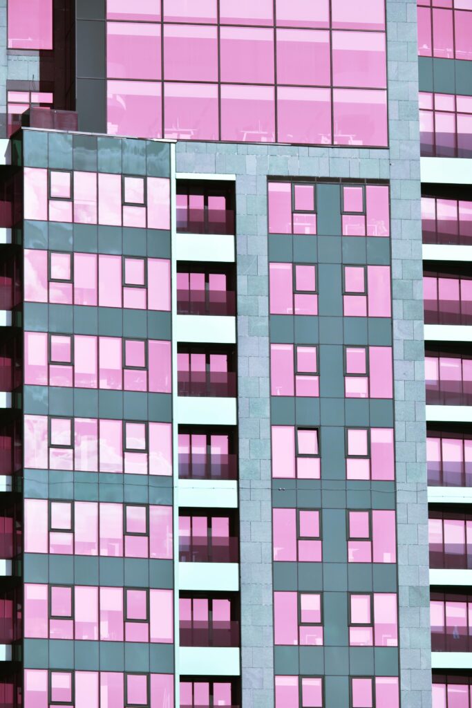 Futuristic building facade with pink glass windows and geometric design.